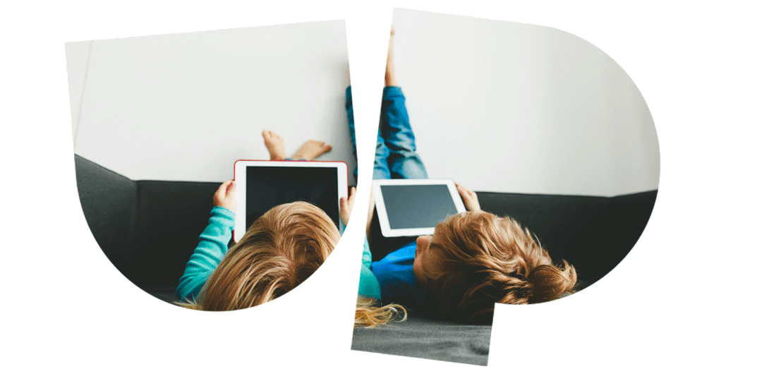 Two children lying on a couch, holding and looking at tablets. Their heads are close, wearing casual clothes, with a white background.