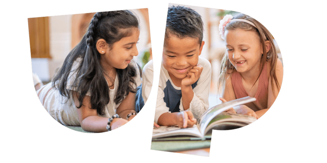 Three children lying on the floor, smiling and reading a book together.