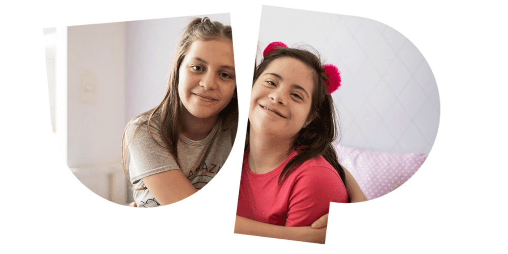 Two girls smiling and hugging, one wearing a gray shirt and the other a pink shirt with pink hair accessories, set against a light background.